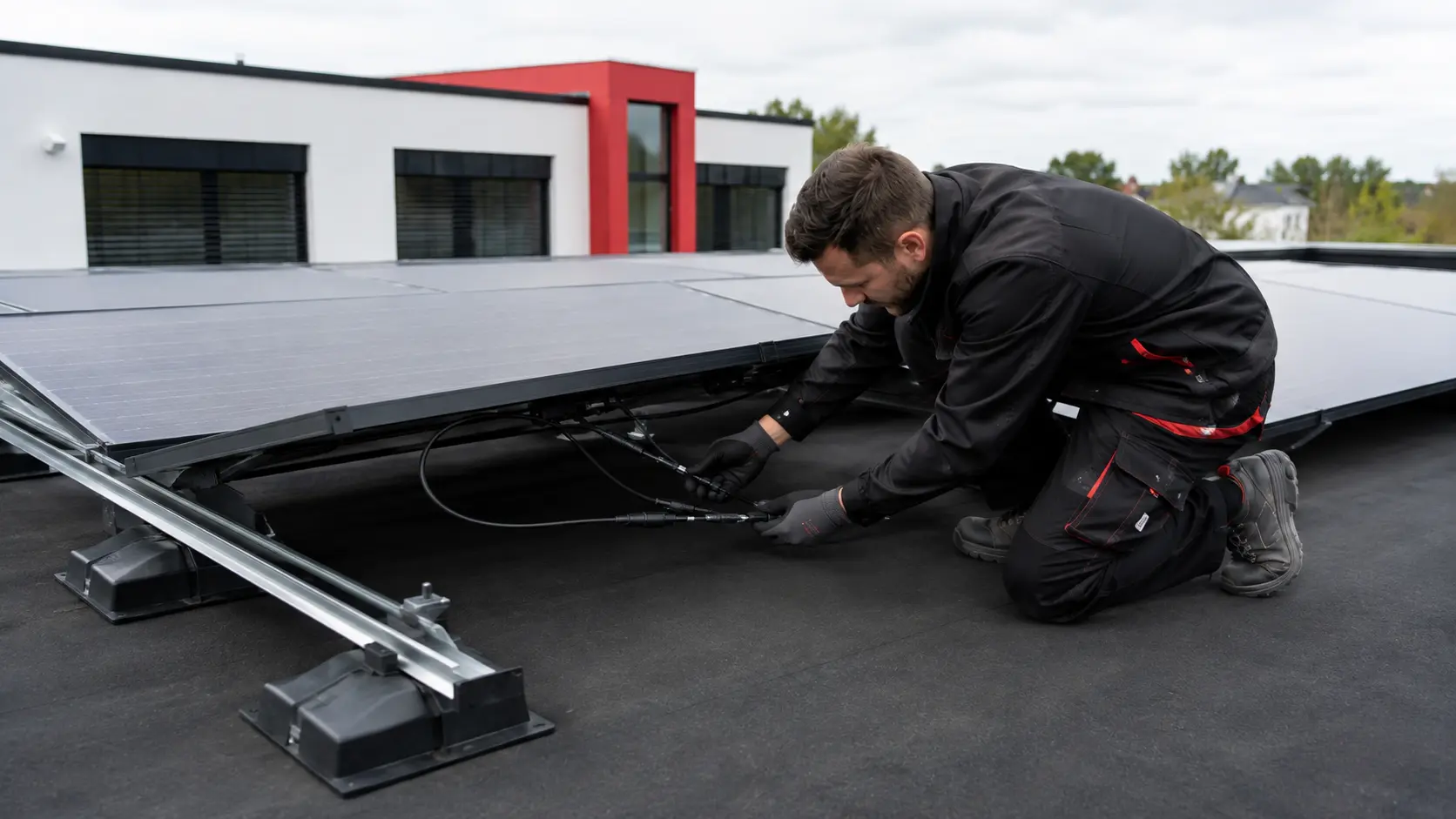 Monteur verbindet die Steckverbindungen der Solarmodule unter der Modulreihe